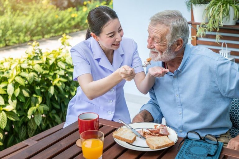nurse-feeding-elderly-senior-man-eat-breakfast-nursing-home_554837-83